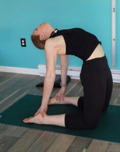 The full version of camel for yoga for runners to improve running posture - chloe is in full hip extension, thoracic extension, and reaching back clasping her heels in camel pose.